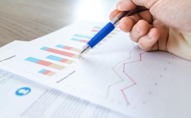 person writing with pen on paper with bar graphs | PLEX