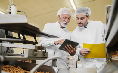 Two Men Examining Documents in Food Manufacturing Plant