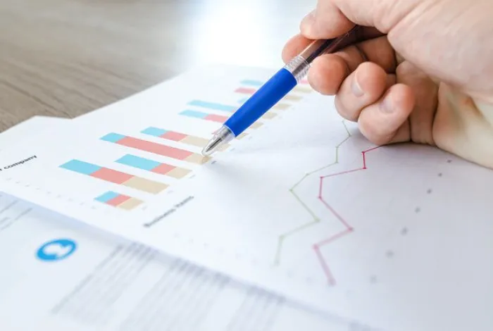 person writing with pen on paper with bar graphs | PLEX