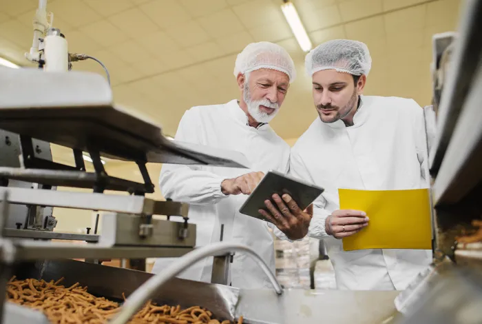 Two Men Examining Documents in Food Manufacturing Plant